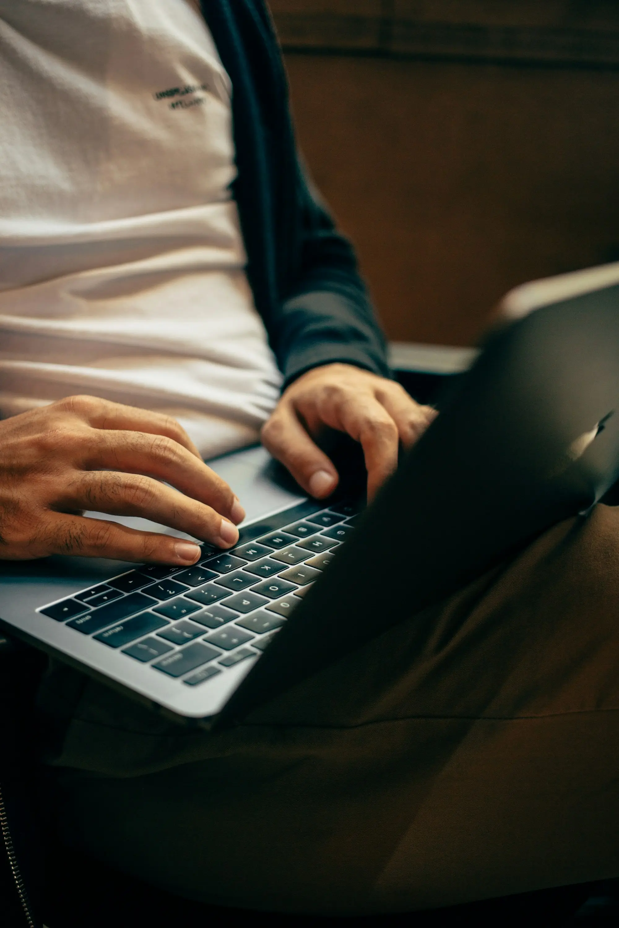 Hands typing on a laptop in low light